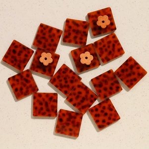 Dettagli macro di ciondoli in resina ambra leopardata con accenti di fiori in legno