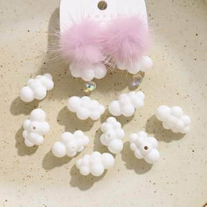 Macro detail of cute white cloud resin charms and pink plush earrings on beige tray