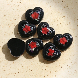 Vue macro de breloques en résine en forme de cœur avec fleurs rouges et paillettes