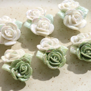 Vue macro de roses 3D en résine nacrée avec feuilles vertes pour la création de bijoux