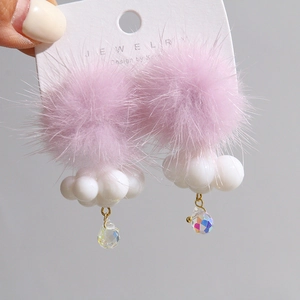 Close-up of fluffy purple pompom earrings with white cloud charms and crystal drops
