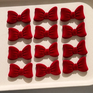 Set of twelve burgundy velvet bows for DIY hair accessories arranged on a white tray
