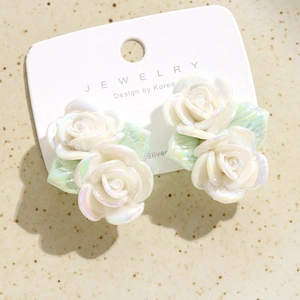 Vue détaillée des boucles d'oreilles roses 3D en céramique avec finition nacrée sur carte