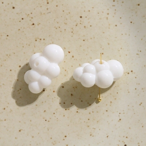 Macro detail of white acrylic cloud charm with gold pin for DIY jewelry making