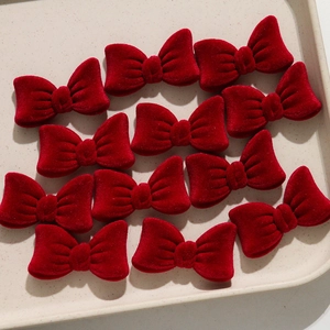 Detailed view of twelve burgundy velvet bow hair clips arranged on a beige display tray