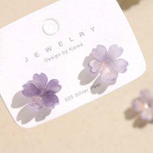 Macro view of 925 silver post stud earrings with purple resin cherry blossoms and glitter