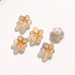 Macro detail of 5 pearlescent acrylic flower beads with orange centers for DIY jewelry