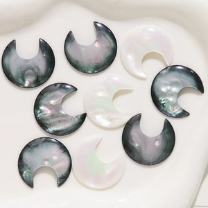 Detailed view of crescent moon shell resin charms with iridescent luster on a white plate