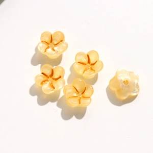 Close-up of five translucent yellow acrylic flower beads for DIY nail art and jewelry