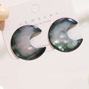 Macro shot of crescent moon earrings with iridescent shell effect on display card