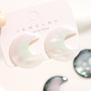 Macro view of moon-shaped iridescent resin earrings on white 925 silver earring card