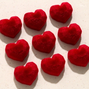 Detailed view of nine red velvet heart-shaped charms for DIY earring accessories