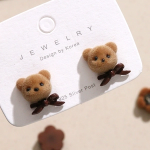 Detail van fluwelen teddybeer oorbellen met bruine strik en 925 zilveren sluiting