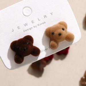 Detailopname van pluizige teddybeer bedeltjes in bruin en kaki met zilveren stekkers