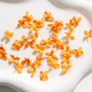 Detail of bright orange fabric Osmanthus flower charms for DIY jewelry and accessories