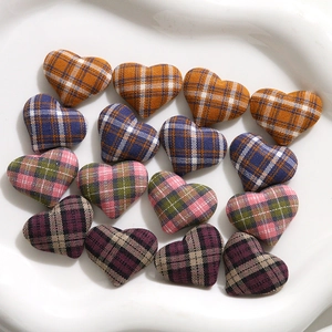 Flat lay of 16-piece plaid fabric heart-shaped buttons in various colors on white plate
