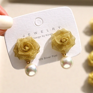 Detailed view of woven metal rose earrings with iridescent white pearls and 925 silver studs