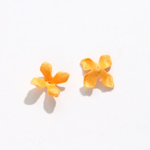 Close-up of handmade orange fabric osmanthus petals with center hole for DIY jewelry