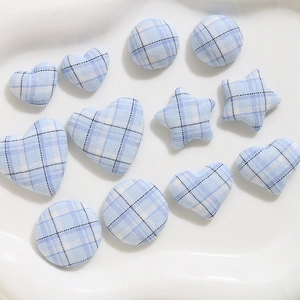 Macro detail of light blue plaid fabric buttons in heart, star and round shapes