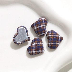 Macro shot of heart-shaped plaid fabric buttons with flat metal back for DIY crafts