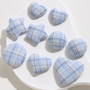 Close-up of light blue plaid fabric charms in heart, star, and round shapes for DIY sewing
