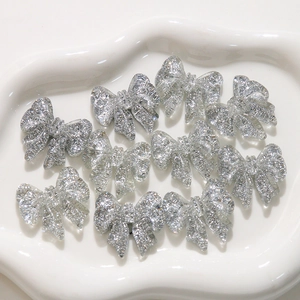 Close-up of sparkling silver glitter bow resin charms for DIY jewelry and crafts