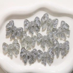 Close-up of sparkling silver bow resin charms for DIY jewelry and nail art