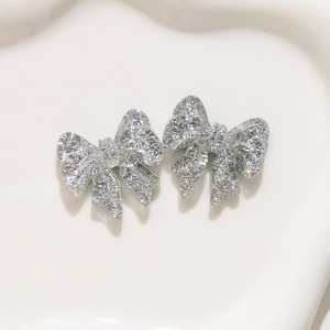 Close-up of sparkling silver bow resin charms with glitter for DIY earrings and jewelry