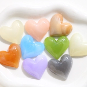 Dettaglio di ciondoli a cuore in resina colorata per fai da te su un piatto di ceramica