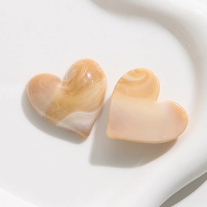 Dettaglio di ciondoli a cuore in resina marmorizzata su un vassoio di ceramica bianca