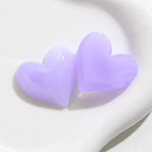 Vista macro di due ciondoli a cuore in acrilico lavanda su superficie in ceramica bianca