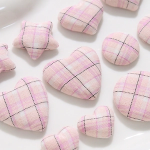 Detailed view of pink plaid fabric heart, star and round buttons for DIY craft projects
