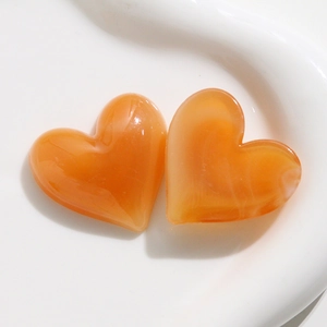 Vista macro di ciondoli a cuore in acrilico arancione semitrasparente per gioielli fai da te