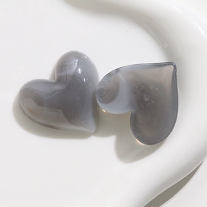 Macro di due perline di acrilico a forma di cuore grigio fumo con texture marmorizzata