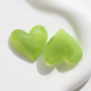 Dettaglio di due ciondoli a cuore in resina verde mela su vassoio in ceramica per fai-da-te