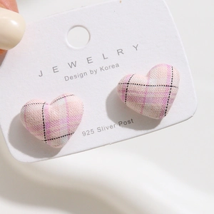 Close-up of heart-shaped earrings with pink plaid fabric wrap on 925 silver posts