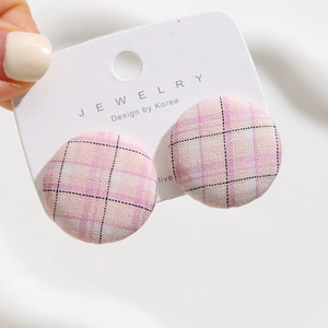 Close-up of pink checkered fabric round button earrings on jewelry display card