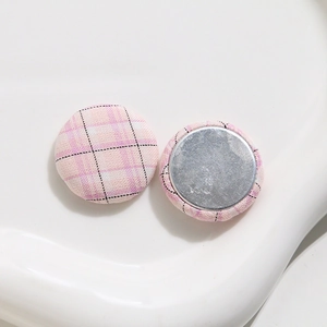 Detail of pink plaid fabric buttons with polished metal base for DIY sewing crafts
