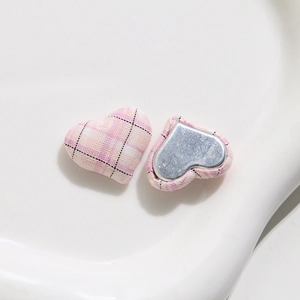Detail of pink plaid fabric heart-shaped button with smooth silver metal base for DIY sewing