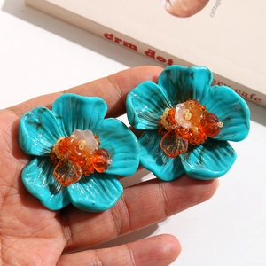 Vue détaillée de grandes boucles d'oreilles fleur en résine bleue avec perles colorées
