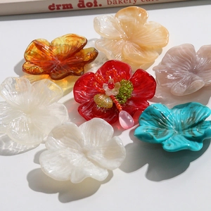 Détail de breloques fleurs en résine ambre et bleu avec centre en perles artisanales