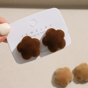 Gros plan sur des boucles d'oreilles fleur en velours marron sur carte design coréenne