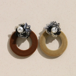 Détail de créoles rétro en velours avec perles tressées et accents floraux gris