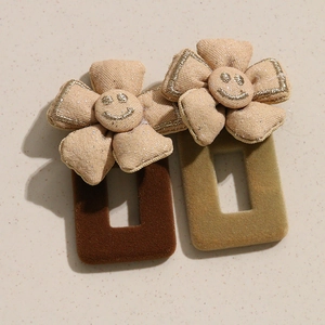 Détail de barrettes à fleurs avec surface floquée et motif de visage souriant brodé