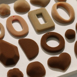 Gros plan de breloques géométriques en velours marron aux formes variées sur un plateau