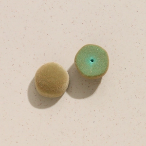 Détail macro de breloques rondes floquées vertes pour la fabrication de boucles d'oreilles