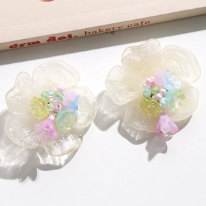 Détail de grandes boucles d'oreilles fleurs en résine avec perles colorées et pétales