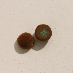Détail de perles ovales floquées marron avec texture velours et trou central pour bijoux