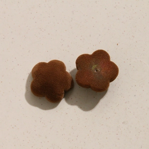Vue macro de pendentifs fleurs floqués marron foncé pour bijoux DIY avec trou central