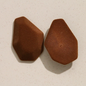 Vue détaillée de deux breloques marron floquées à facettes sur une surface en pierre